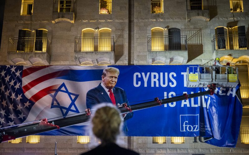 Workers hang a large banner featuring a picture of U.S. President Donald Trump in Jerusalem, October 12, 2025. Photo by Yonatan Sindel/Flash90 *** Local Caption *** דגל ארה״ב
ירושלים
נשיא ארצות הברית
דונלד טראמפ
ביקור
הסכם
מלחמה
עזה
ישראל